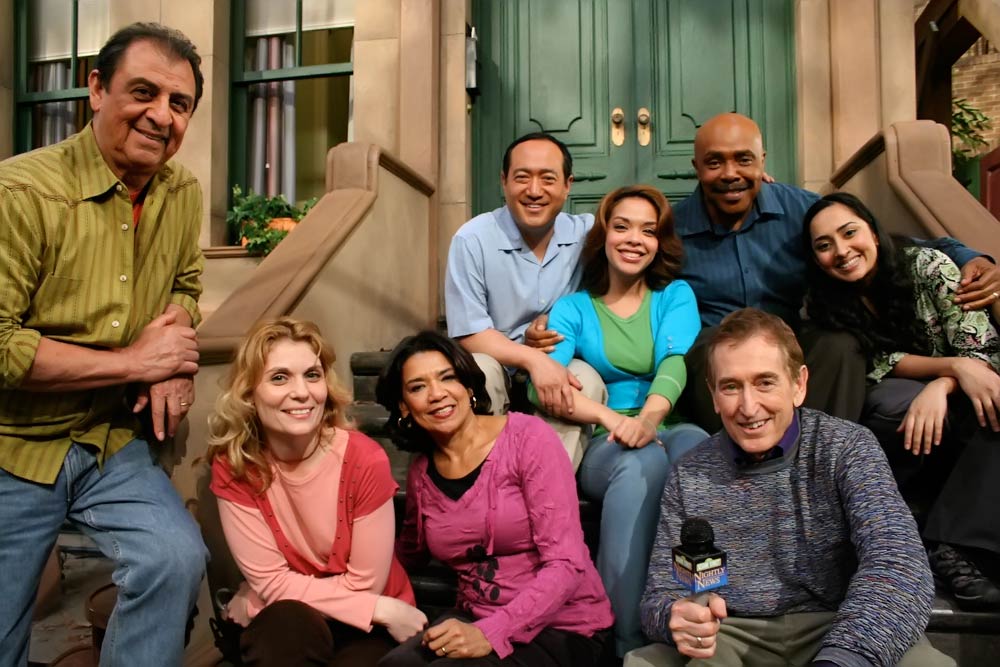 Sesame street cast sitting on the stoop of the set